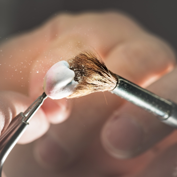 Small brush being used to clean a dental crown