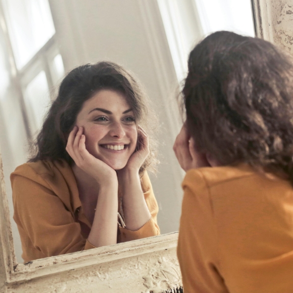 Smiling woman looking at her face in her mirror