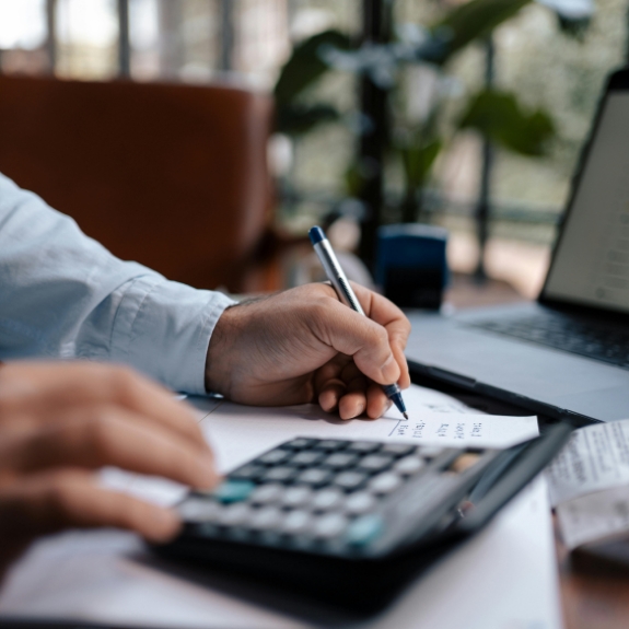 Person typing on a calculator while writing on a paper