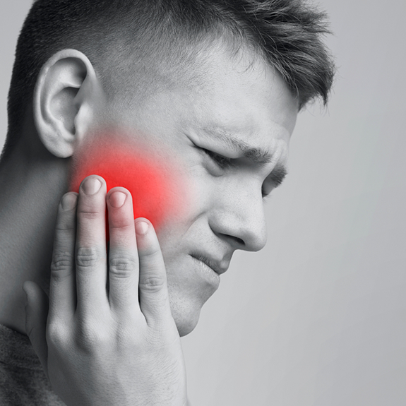 Man wincing while holding his cheek in pain