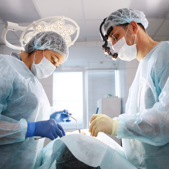 Dentist and assistant performing dental implant surgery on a patient
