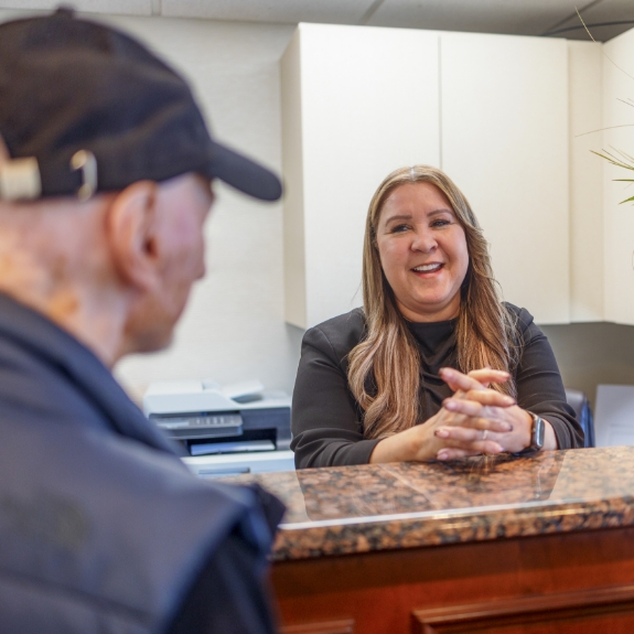 Man talking to dental office receptionist at front desk