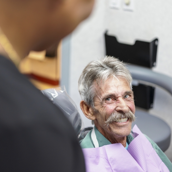 Senior dental patient smiling at his dentist