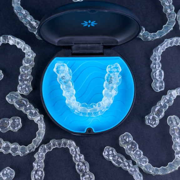 Several Invisalign aligners scattered on a table with two in their case