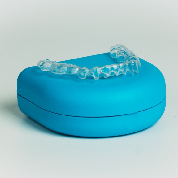 Invisalign aligner resting on tops of its blue case