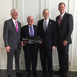 Doctor Mohr holding a plaque next to three other men in suits