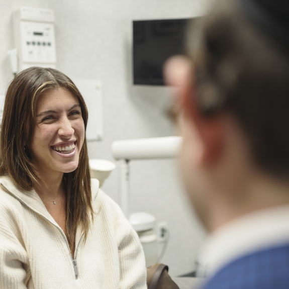 Woman in the dental chair grinning at Doctor Ariel