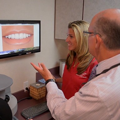 Dentist and patient looking at smile design photos