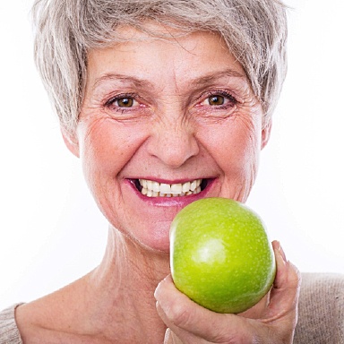 Woman eating an apple with best Long Island implant dentist, Dr. Allan Mohr