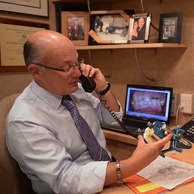 Long Island dental implant dentist, Dr. Allan Mohr, talking with oral surgeon on phone