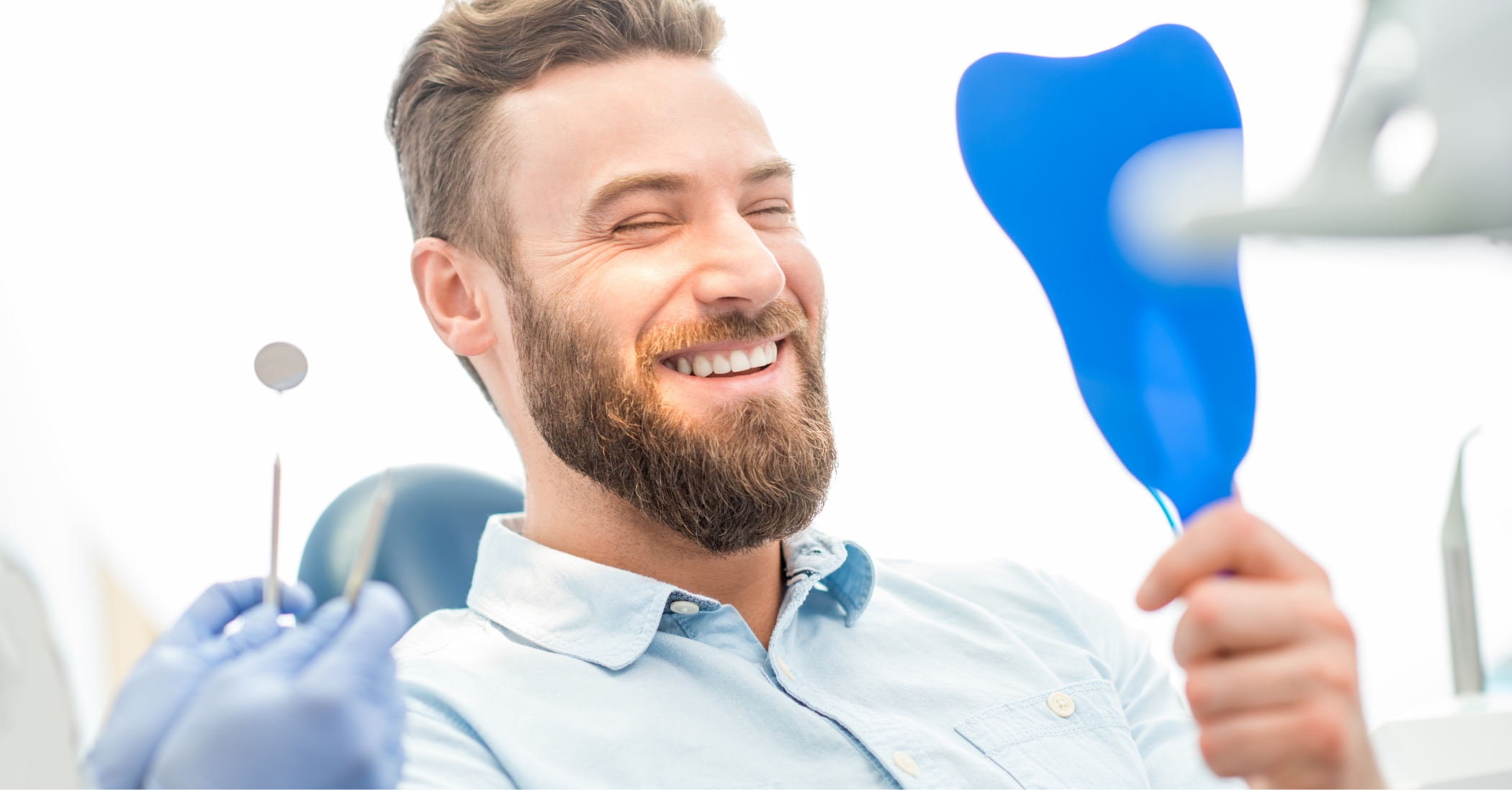 Dental patient admiring his new smile in a mirror with overdentures in Massapequa Park