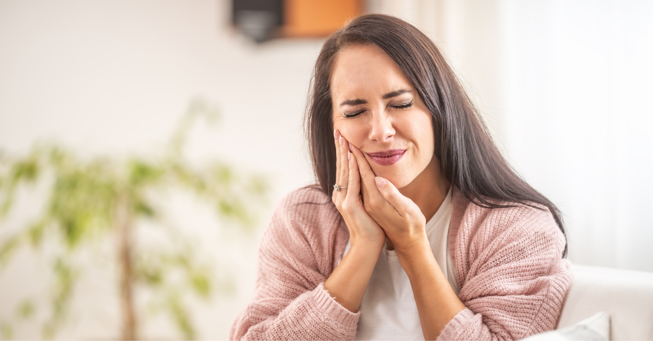 Woman holding her cheek in pain before getting root canal treatment in Massapequa Park