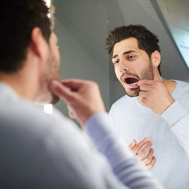 Man looking at dental implant in the mirror 