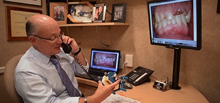Dentist talking on phone and holding smile model